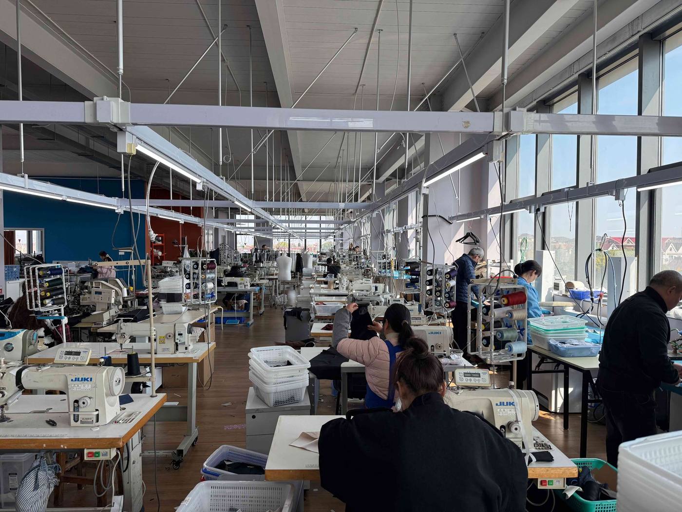 Reparto di confezione del laboratorio di Shanghai: lunghe file di macchine da cucire e sarti al lavoro